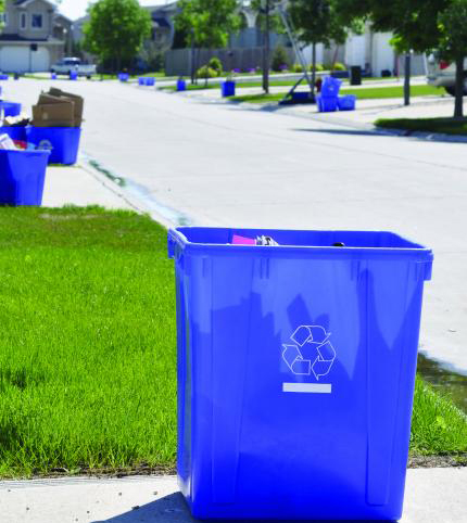 Close up of blue box recycling bin sitting at the end of driveway