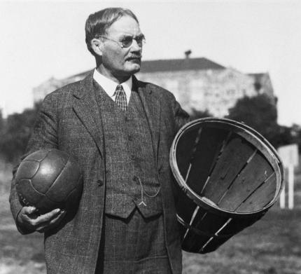 Black and white photo of James Naismith holding peach basket and basketball