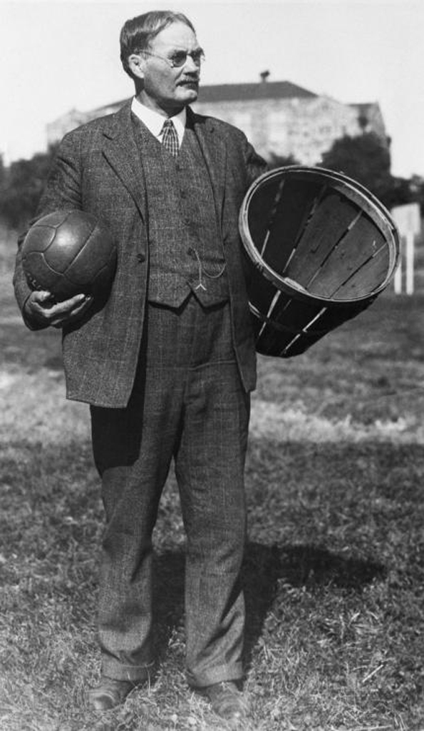 Photo noir et blanc de James Naismith tenant un panier de pêche et un basketball