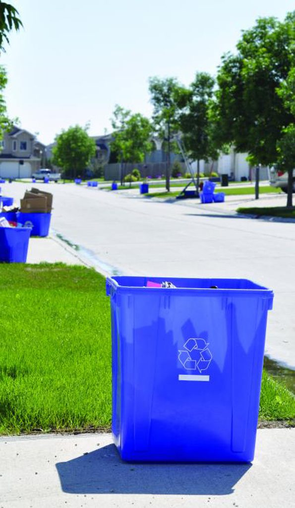 Close up of blue box recycling bin sitting at the end of driveway