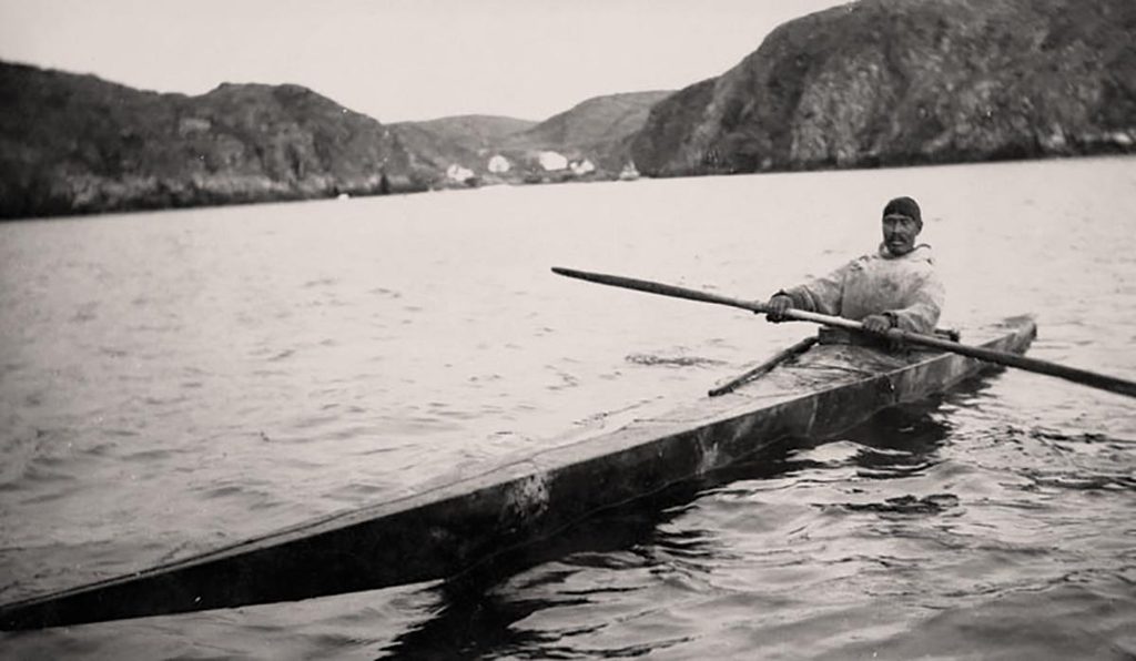 Inuit man on a lake in the first kayak