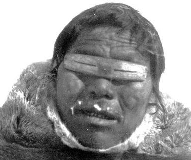 Inuit man wearing snow goggles he made out of bone