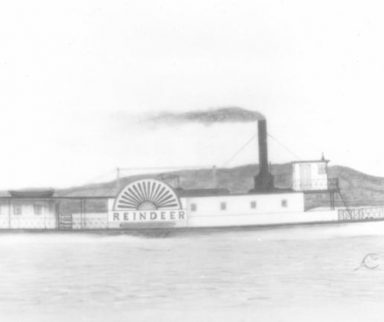 Old black and white image of a steamboat cruising down a river