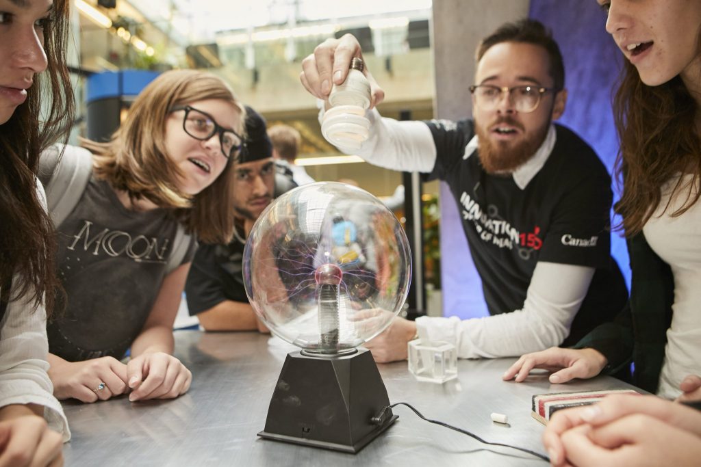 Instructor showing plasma ball experiment to high school kids