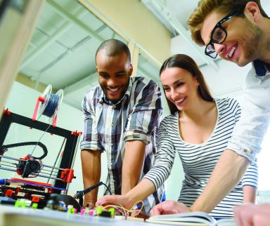 Young engineers using a 3D printer in an office