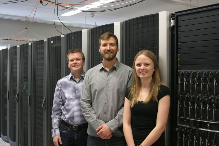 Server room with three profs standing in front of them