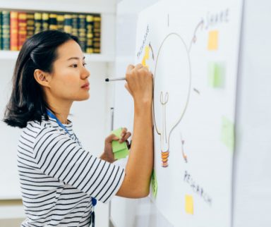 woman adding ideas on a white board