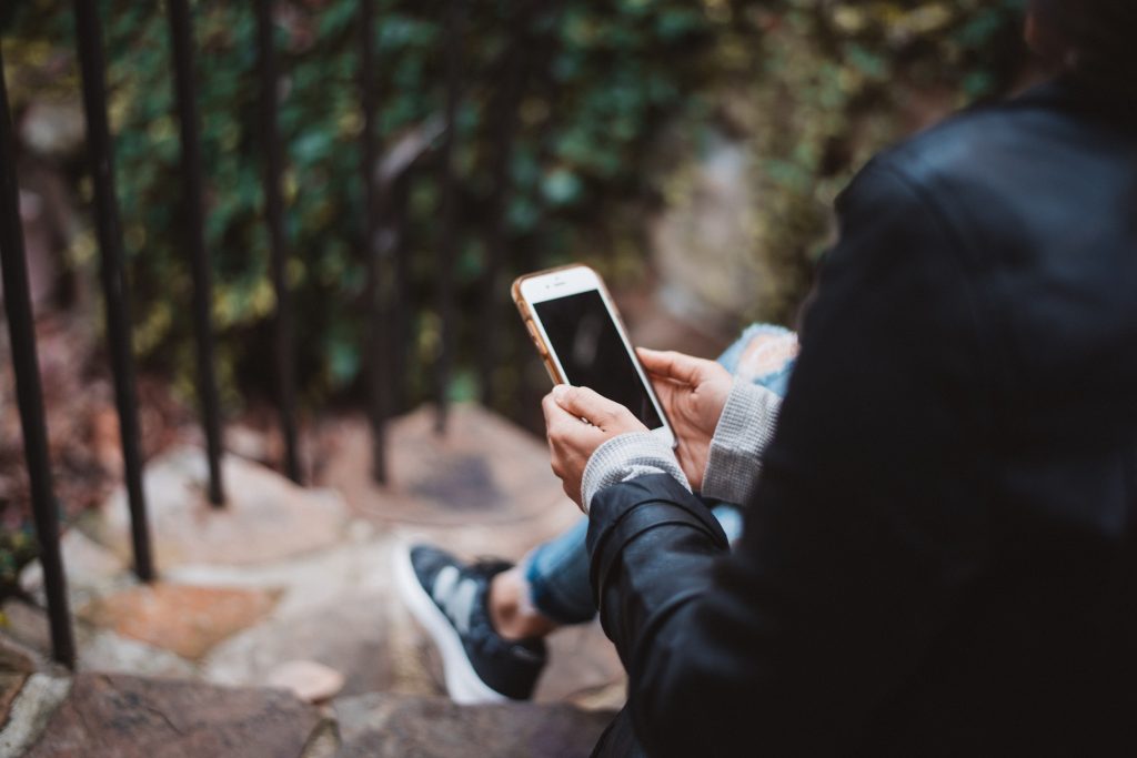 woman in forest sitting with smart phone