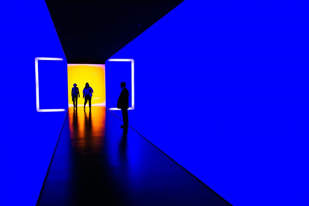 shadows in a blue and yellow lit corridor