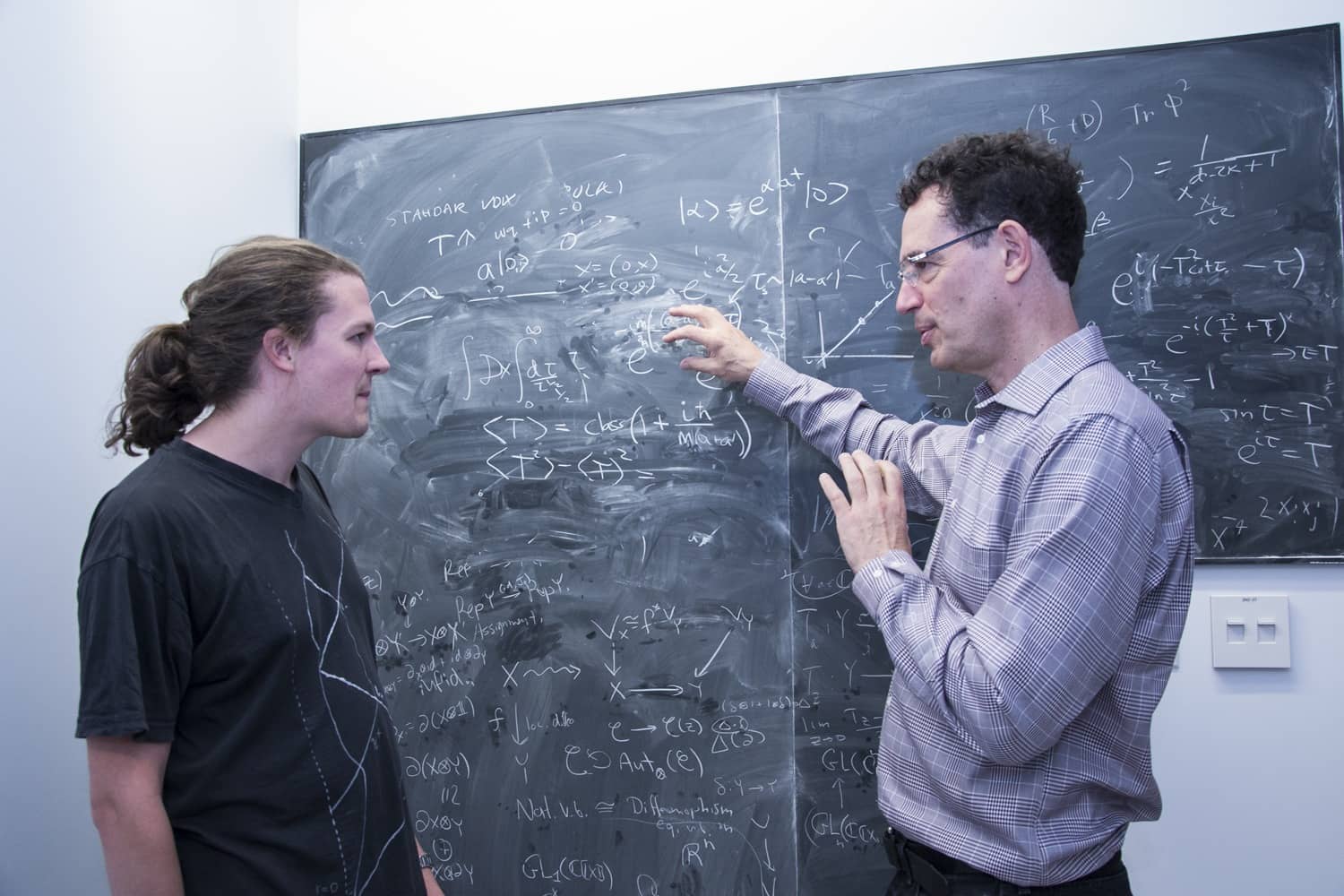 Director and student talking in front of a blackboard