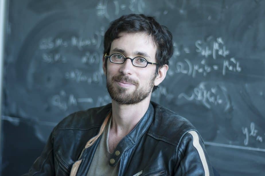 Portrait of a man sitting in front of a blackboard filled with equations