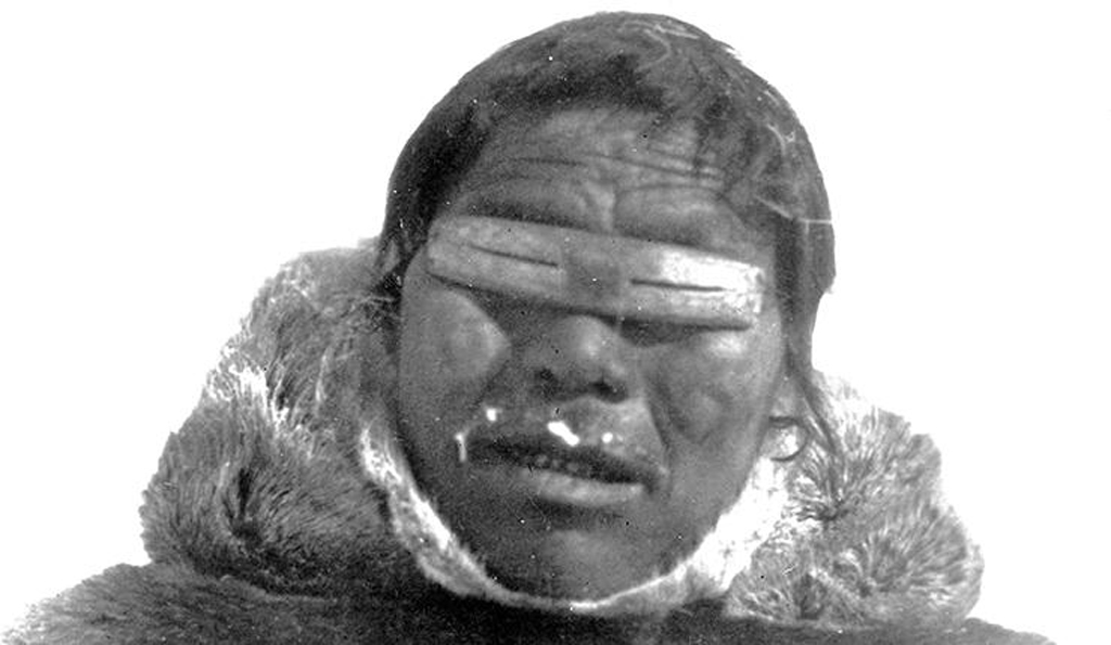 Inuit man wearing snow goggles he made out of bone